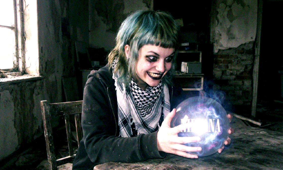 A young woman with colorful hair dyed in washed out blue-green coloring blended with brown olive drab. She has black makeup, and a bob cut with a fringe that doubles as a mullet. She has a nose piercing, and a keffiyeh. She is firmly grasping a crystal ball, giving an exaggerated evil grin with unnatural proportions. Inside the glowing crystal ball, the text "NIRVANA" can be seen floating.
